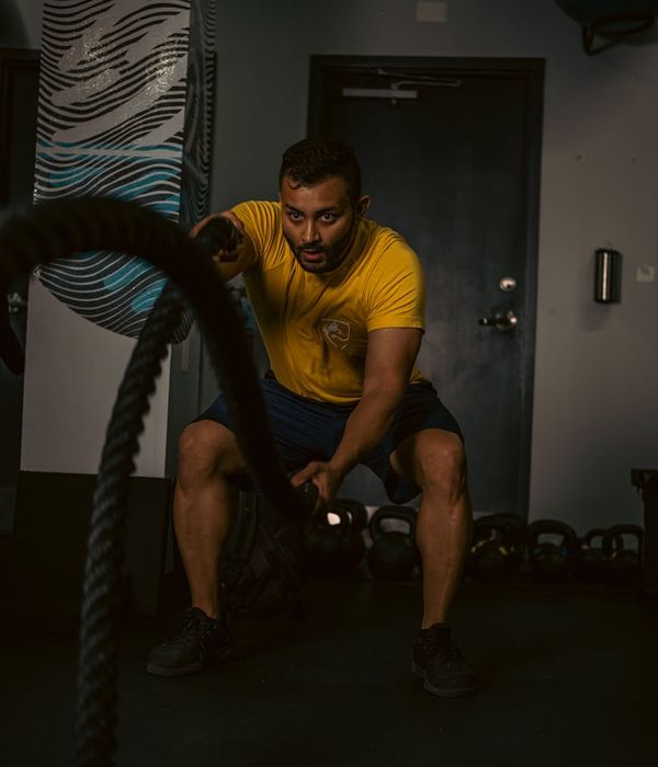 Man performing dynamic movement exercise in a dark modern gym environment